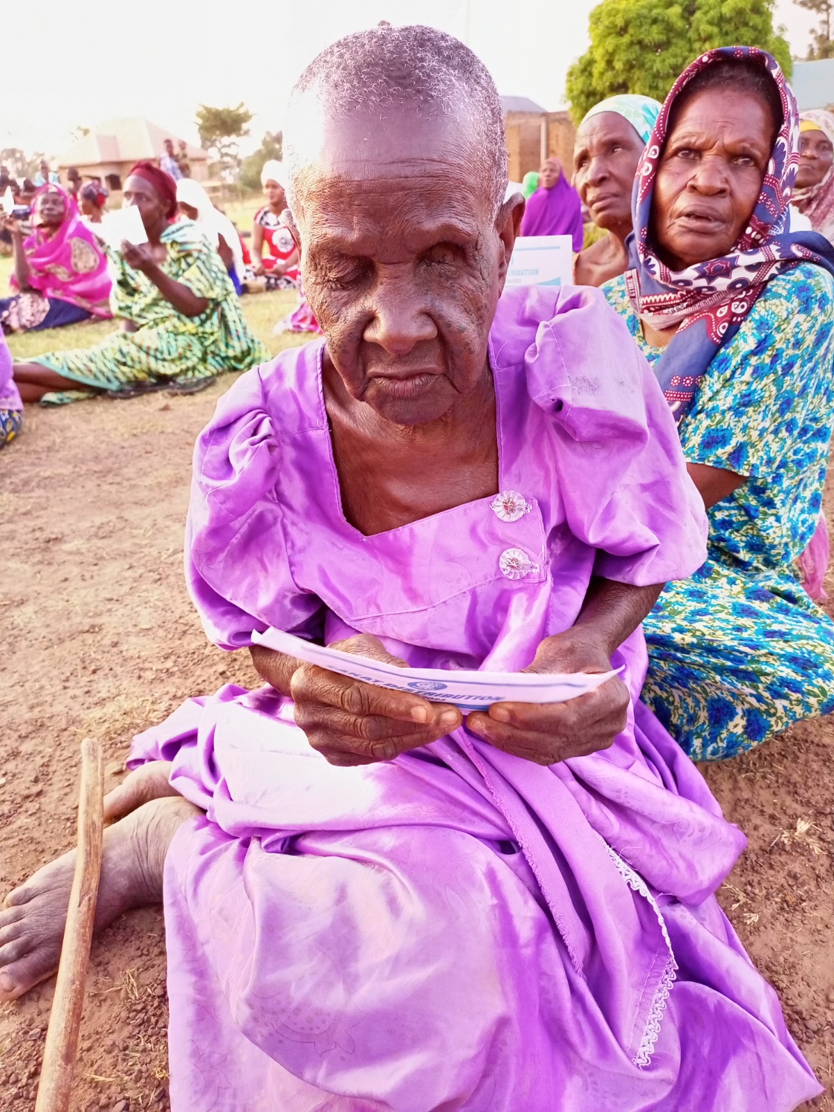 Elderly woman holding a distribution slip during an aid event