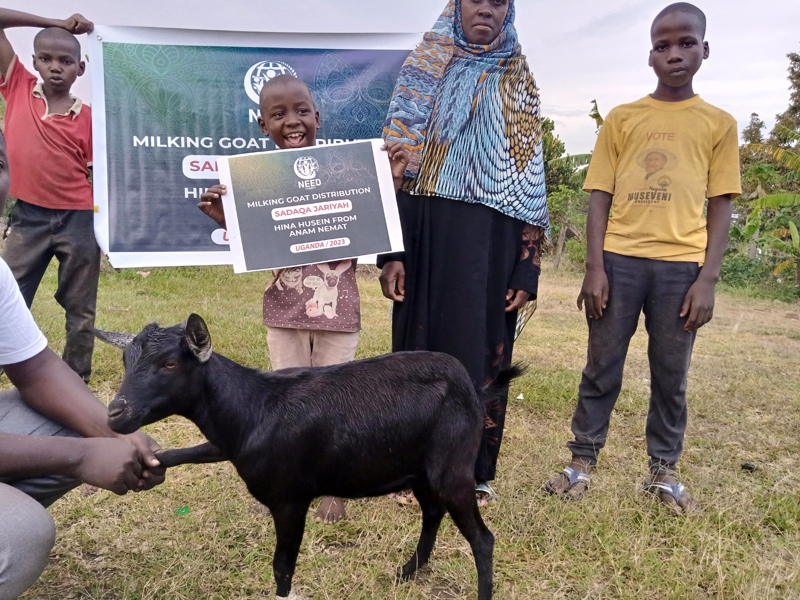 Milking goat distribution with beneficiaries holding project banners