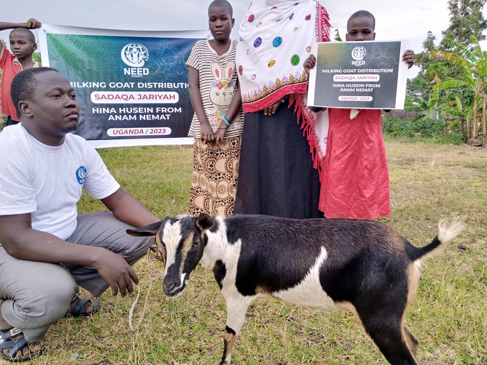 Family receiving a milking goat with project signage